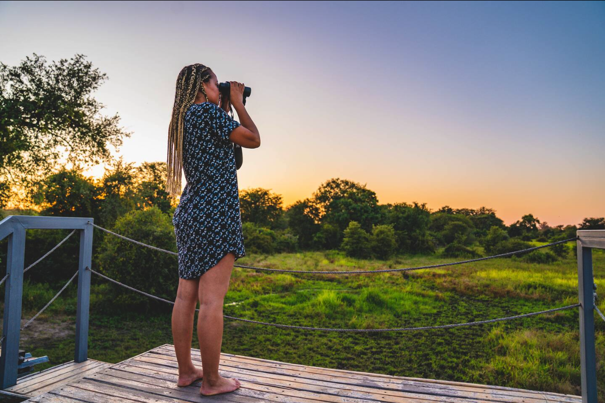 Guest scanning the bush with binoculars from the rooftop deck