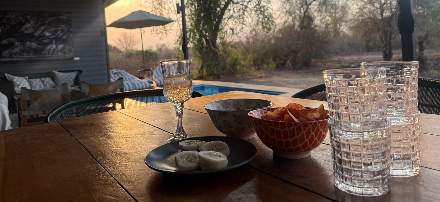 Sundowner setup on the veranda with pool and bush view at golden hour